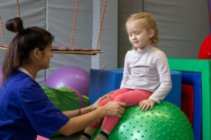 Little blonde girl sitting on big gym ball working