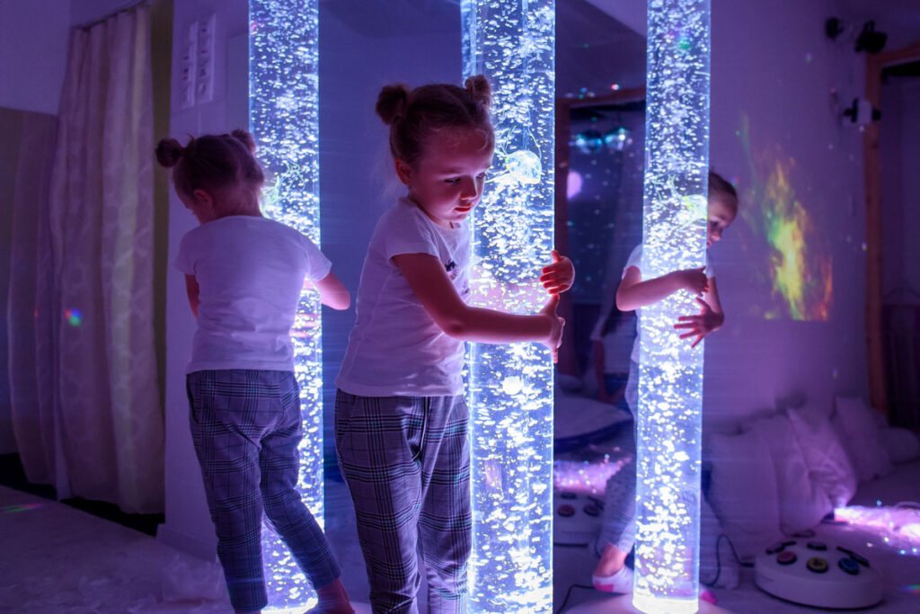 Deafblind child interacting with coloured lights bubble tube lamp.