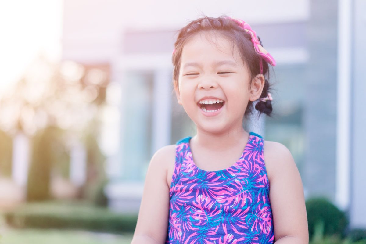 Blind little girl in a purple dress smiling.