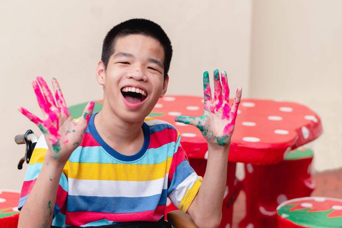 Blind disabled child smiling with hands stained with paint